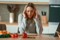 Tired, having headache. Beautiful young woman is on the kitchen