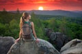 Tired hiker girl relaxing on rocky mountain top enjoying evening nature during travelling on wilderness trail. Lonely Royalty Free Stock Photo