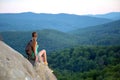 Tired hiker girl relaxing on rocky mountain top enjoying evening nature during travelling on wilderness trail. Lonely Royalty Free Stock Photo