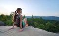 Tired hiker girl relaxing on rocky mountain top enjoying evening nature during travelling on wilderness trail. Lonely Royalty Free Stock Photo