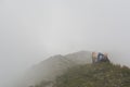 Tired hiker lies on a mountain ridge in a thick fog