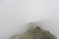 Tired hiker lies on a mountain ridge in a thick fog