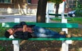 Tired homeless man sleeping on a bench