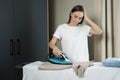 Tired housewife irons clothes on an ironing board. Tired woman housewife ironing clothes iron in laundry Royalty Free Stock Photo