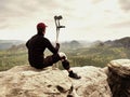 Tired hurt tourist with medicine crutches. Man with broken leg in knee brace features resting on exposed rocky summit Royalty Free Stock Photo