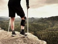 Tired hurt tourist with medicine crutches. Man with broken leg in knee brace features resting on exposed rocky summit Royalty Free Stock Photo