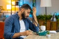 Tired Indian man freelancer talking on retro wired telephone annoyed boring conversation at office Royalty Free Stock Photo