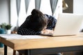 Tired Indian woman sleeping, sitting at desk with laptop