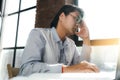 A tired Korean office worker is working on a laptop and holding his head in headache. Office work