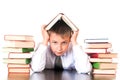 A tired, lagging schoolboy boy sits in a library with books and learns lessons. Unwillingness to learn