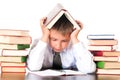 A tired, lagging schoolboy boy sits in a library with books and learns lessons. Unwillingness to learn
