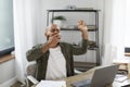 Tired latin male entrepreneur yawning, sitting at workplace with laptop computer, wanting to sleep in home office Royalty Free Stock Photo