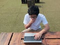 Tired laziness young Asian man using computer laptop at outdoors. Internet of things concept Royalty Free Stock Photo