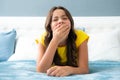 Tired lazy teenager girl yawning in bed. Sleepless child wake up on bed and yawning feeling tired. Royalty Free Stock Photo