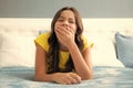 Tired lazy teenager girl yawning in bed. Sleepless child wake up on bed and yawning feeling tired. Royalty Free Stock Photo