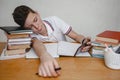 Tired of lessons, a teenager at home for textbooks looks at a smartphone Royalty Free Stock Photo