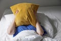 tired listless person lying in bed and hiding face under pillow Royalty Free Stock Photo