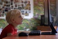 Tired little blond boy sits his nose buried in a monitor PC. Internet and preschooler