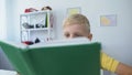 Tired little boy reading schoolbook and putting head on desk, education concept