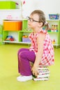 Tired little girl sitting on stack of books Royalty Free Stock Photo