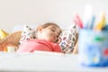 Tired little preschooler girl sleeping in comfortable chair near desk Royalty Free Stock Photo