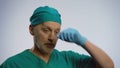 Tired male doctor sighing deeply, taking off medical face mask, mopping his brow