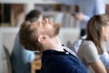 Tired male employee falling asleep in chair at workplace