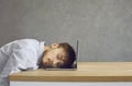 Tired male office worker sleeping sitting at a desk putting his head on a laptop keyboard. Royalty Free Stock Photo