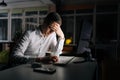 Tired male office worker working late at night, using desktop computer and touching forehead. Exhausted businessman Royalty Free Stock Photo