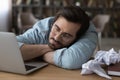 Tired male writer lie on desk sleep among crumpled papers