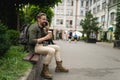 Tired man with backpack sitting on bench while engaged in conversation on mobile phone. Weariness on face suggests that Royalty Free Stock Photo