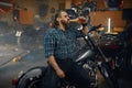 Tired man biker drinking beer from bottle after hard repair work in garage