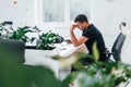 Tired man in black clothes have work in the office. Sitting by the table