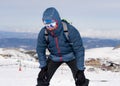 Tired man exhausted after peak summit trekking achievement in snow mountain winter landscape