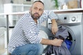 tired man loading clothes into washing machine at home Royalty Free Stock Photo