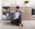 Tired man beside open dishwasher Royalty Free Stock Photo