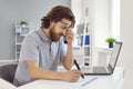 Tired man is overworked and has pain in his eyes from working on laptop in office. Royalty Free Stock Photo