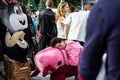 tired man in a pink piggy costume sleeps in the middle of the crowd