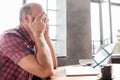 Tired man rubbing his eyes near laptop computer sitting in the living room. Royalty Free Stock Photo