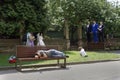 Tired Man sleeping on a bench while photographer taking pictures for wedding procession