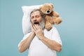 Tired man sleeping at home having too much work. Bored businessman with pillow and toy bear Royalty Free Stock Photo