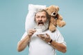 Tired man sleeping at home having too much work. Bored businessman with pillow and toy bear Royalty Free Stock Photo