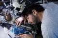 A tired man is sleeping on a large bunch of various electronic components in a lab Royalty Free Stock Photo
