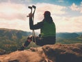 Tired man tourist sit with hurt knee in immobilizer or rock, hold medicine pole. Open forest landscape Royalty Free Stock Photo