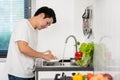 Tired man washing dishes in the sink in kitchen at home Royalty Free Stock Photo