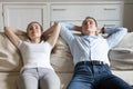 Tired man and woman relaxing on sofa hands over head Royalty Free Stock Photo