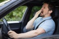 Tired man yawning on front seat car Royalty Free Stock Photo