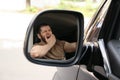 Tired man yawning in auto, view through car side mirror