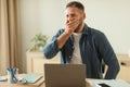 Tired man yawning while sitting at laptop in modern office Royalty Free Stock Photo