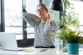 Tired mature business woman with neck pain looking uncomfortable while working with laptop on a desk in the office at home Royalty Free Stock Photo